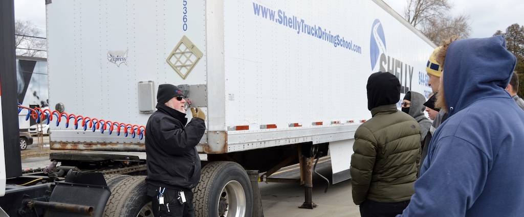 Truck driving instructor with students outside.