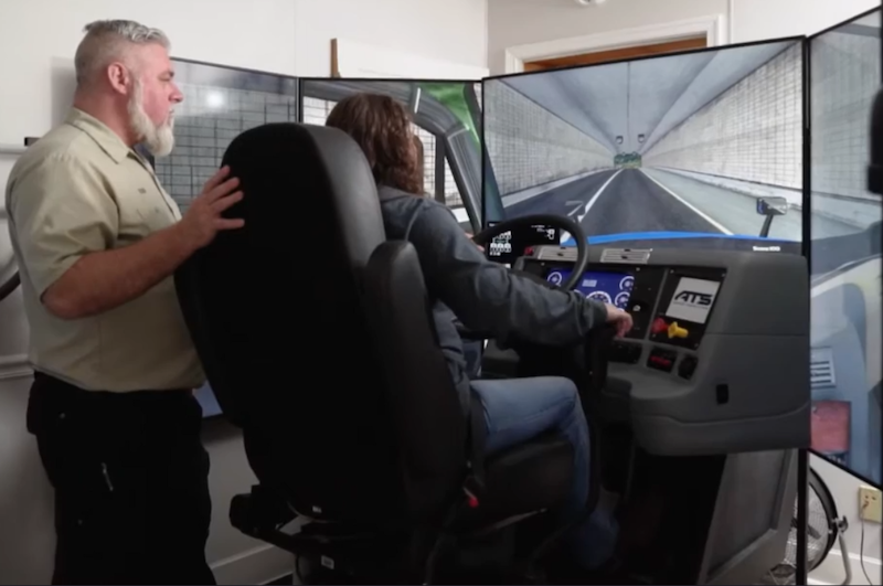 Truck driving instructor with a student using the simulator.
